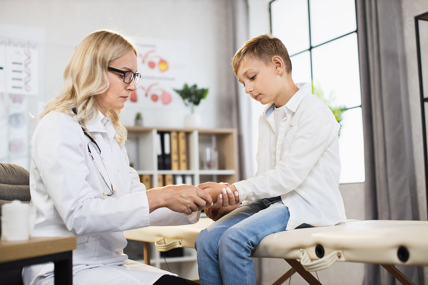 Teenage boy having medical consultation with competent doctor at modern clinic. Female physician examining male patient at own cabinet. Concept of health care.