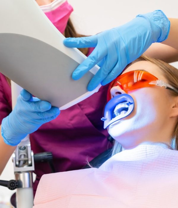 A woman undergoes teeth whitening and the application of a UV lamp for the bleaching process.