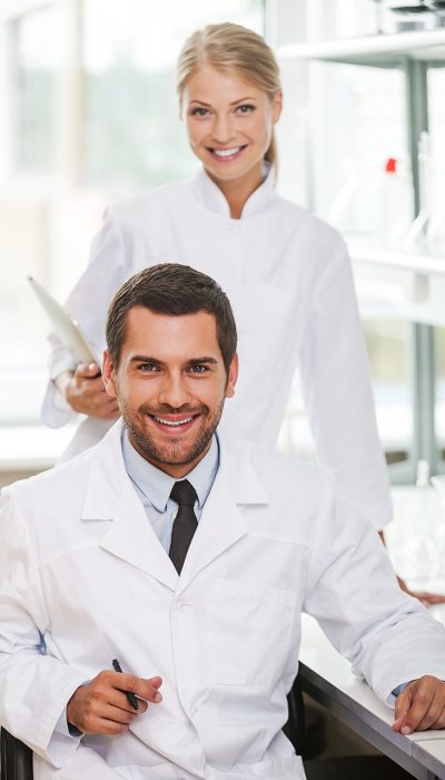 Medical experts. Two happy young scientists looking at camera and smiling while working together in the laboratory