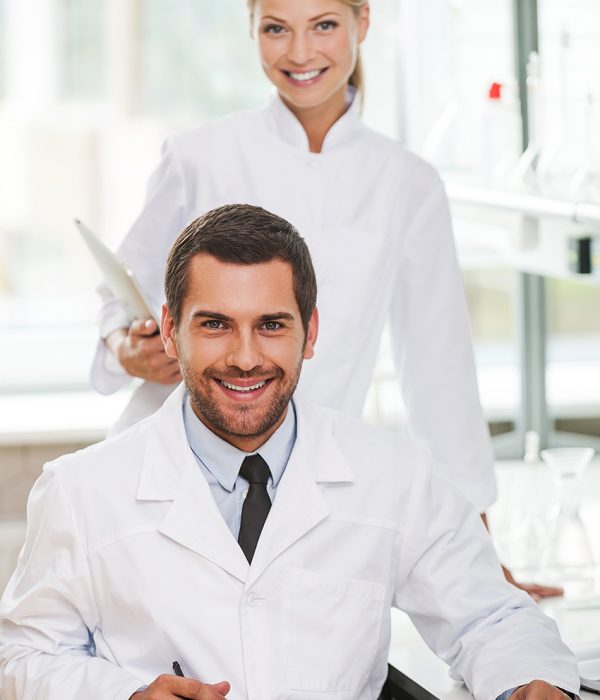 Medical experts. Two happy young scientists looking at camera and smiling while working together in the laboratory